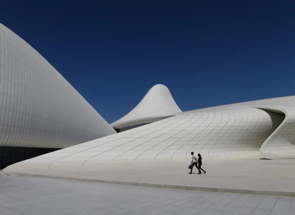 Two people walk across the plaza at the Zaha Hadid designed Heydar Aliyev Center in Baku, Azerbaijan