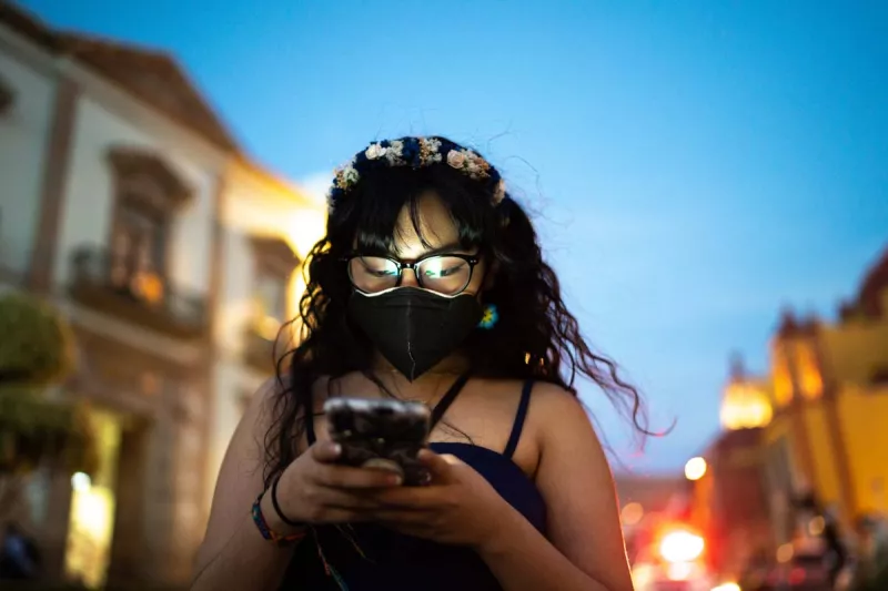 Spica Telecom planea adquirir espectro (Mujer revisando su teléfono en la calle)