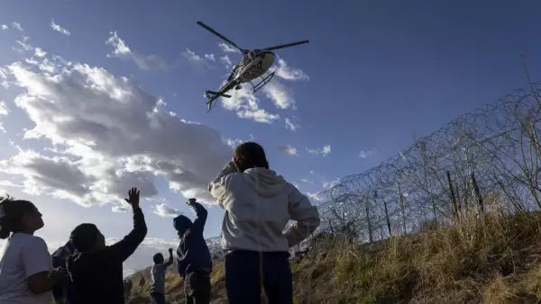 Migrantes de Venezuela y Colombia saludan a un helicóptero del Departamento de Seguridad Pública mientras sobrevuela en El Paso, Texas, el 2 de abril de 2024.