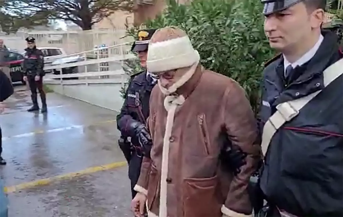 Esta captura de video del folleto tomada y publicada por la Oficina de Prensa de los Carabinieri italianos el 16 de enero de 2023 muestra el traslado del jefe de la mafia más buscado de Italia, Matteo Messina Denaro (C) de la estación de policía de los Carabinieri de San Lorenzo en Palermo, a un lugar no revelado, después de su arresto en su Sicilia natal el 16 de enero de 2023 después de 30 años huyendo.