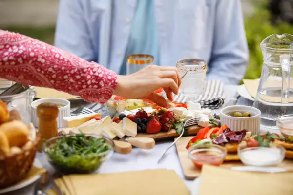 Woman reaching for a piece of cheese served on a charcuterie board