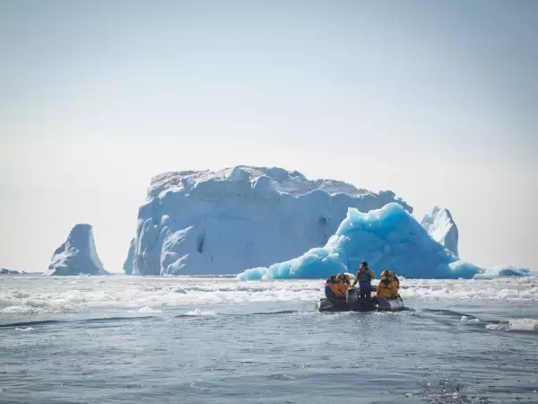 Integrantes del crucero Zodiac de Groenlandia visitando en lancha icebergs