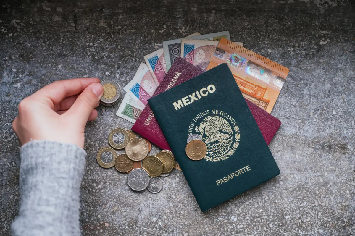 Contando dinero de diferentes países y un pasaporte mexicano y un pasaporte rumano en un lado.