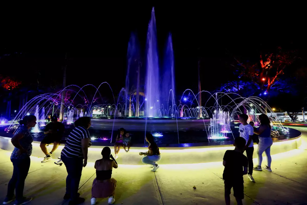 La gente disfruta de una fuente iluminada con luces de colores después de un corte de energía a nivel nacional, en Valencia, Venezuela, el 30 de agosto de 2024. 