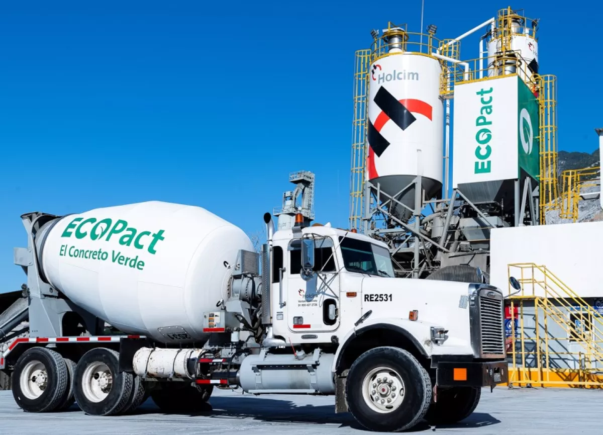 Camión con olla revolvedora de cemento y al fondo se observa la planta de Holcim.