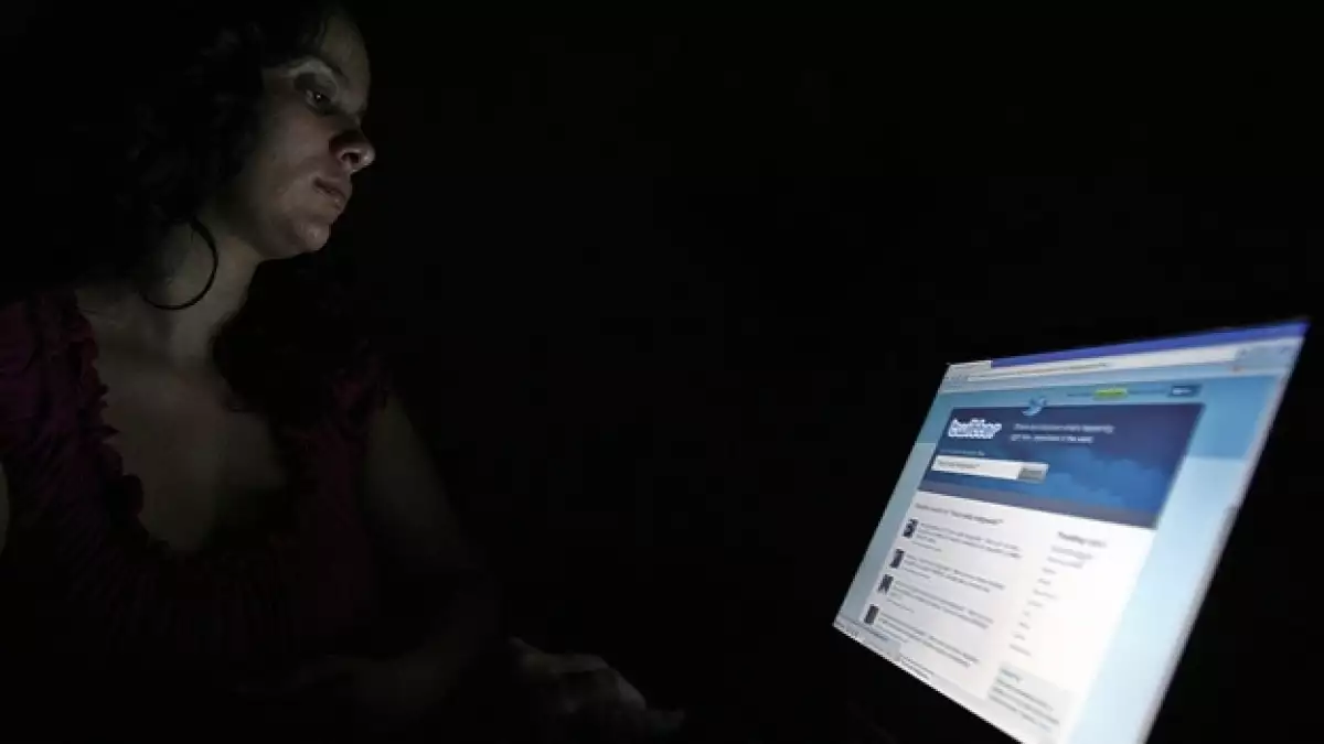 una chava frente a una pantalla donde se ve la pagina de twitter