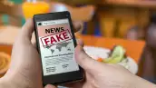 unas manos sostienen un celular que en la pantalla dice fake news