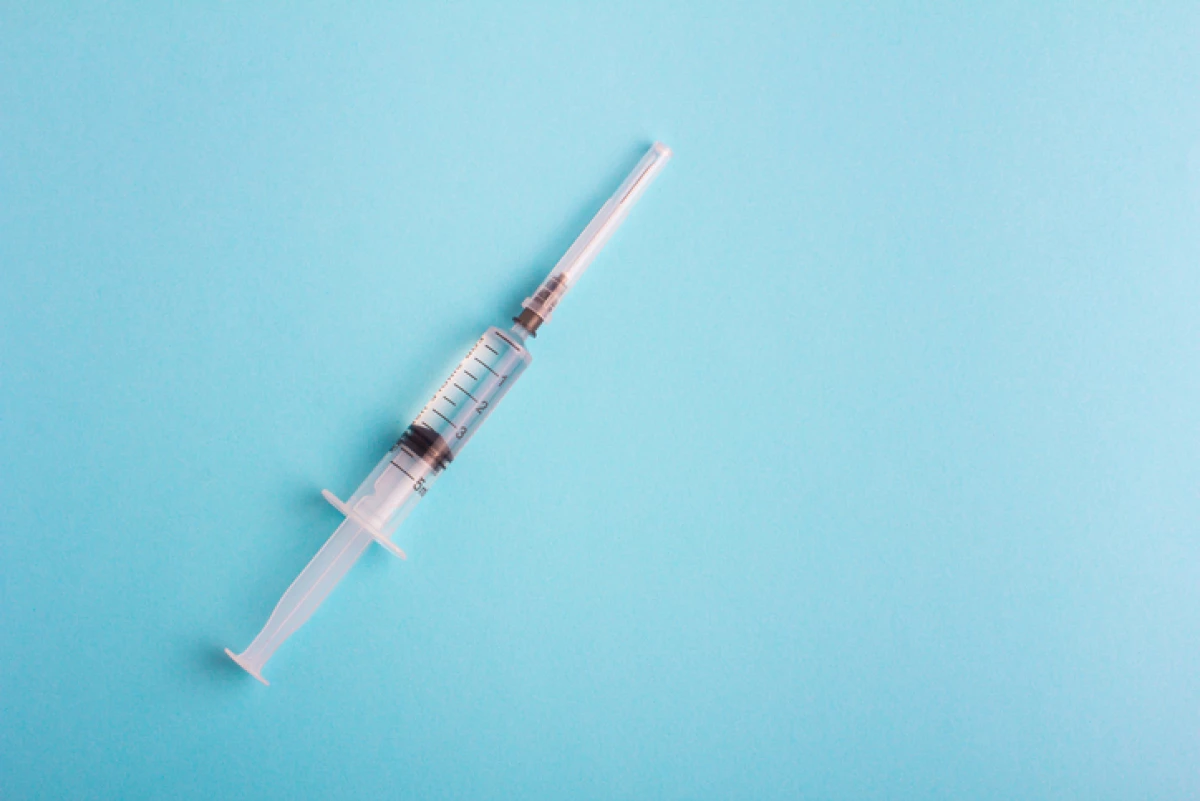 Syringe with lid on blue background
