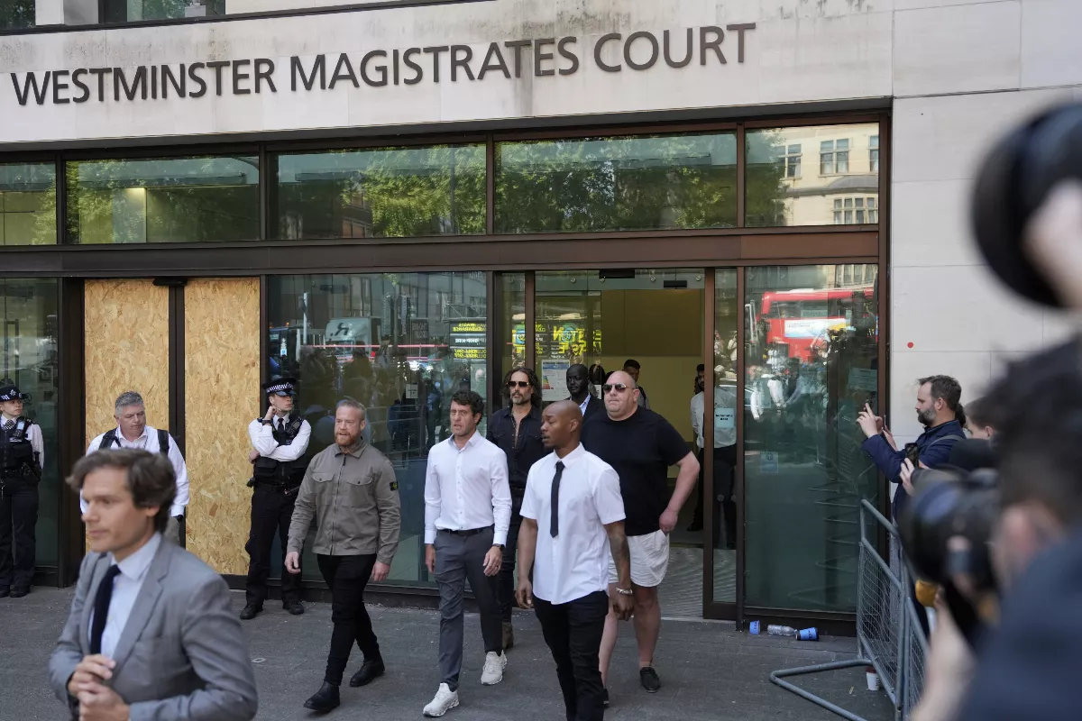 Foto de Russell Brand rodeado de sus abogados al salir de la Corte de Westminster, Inglaterra.