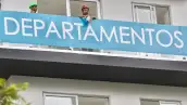 Dos trabajadores se asoman en un balcón de un edificio de departamentos en venta en CDMX.