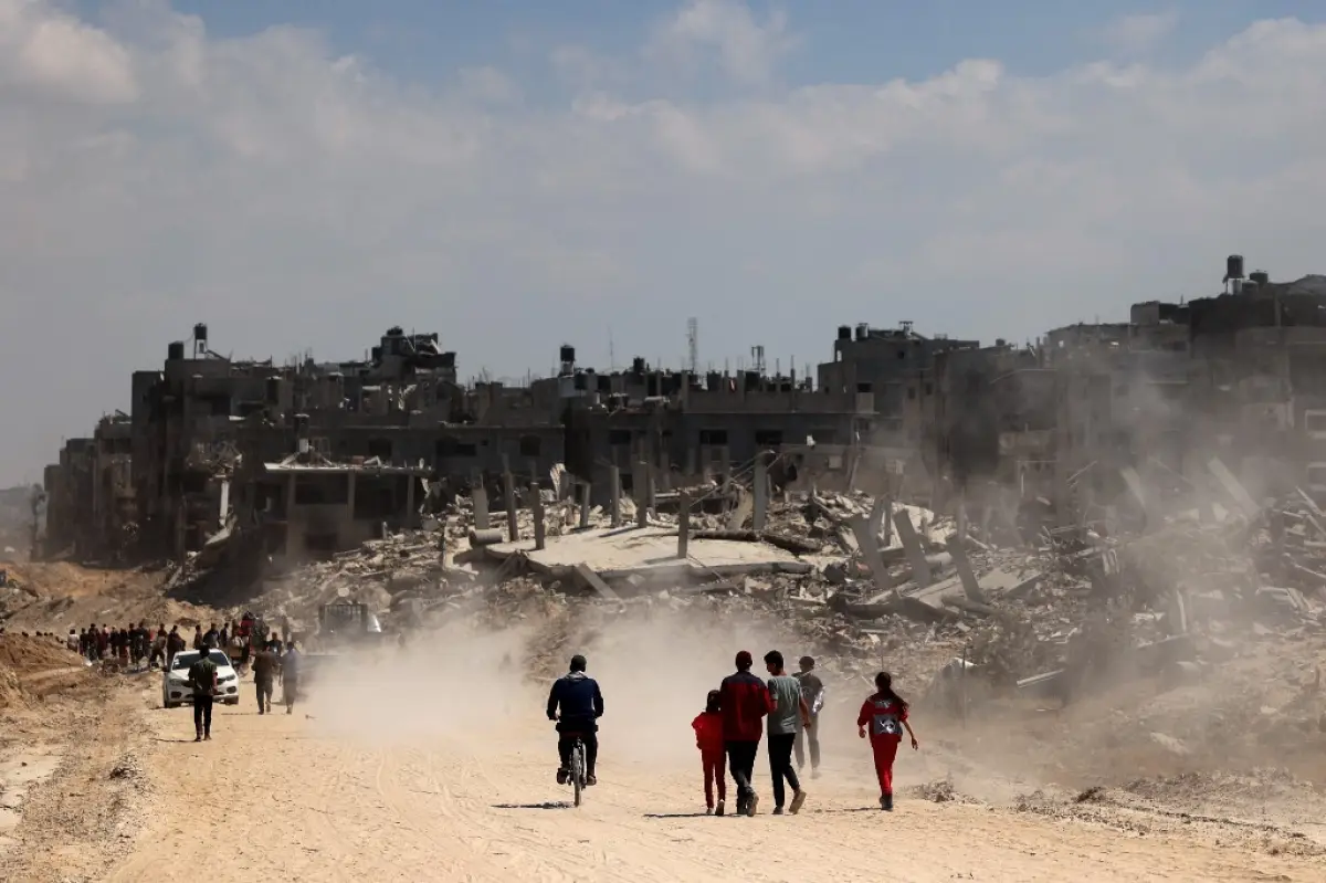 Los palestinos utilizan una carretera bordeada con edificios dañados y destruidos en Khan Yunis el 7 de abril de 2024 después de que Israel retirara las tropas del sur de la Franja de Gaza, seis meses después de la devastadora guerra tras los ataques del 7 de octubre.
