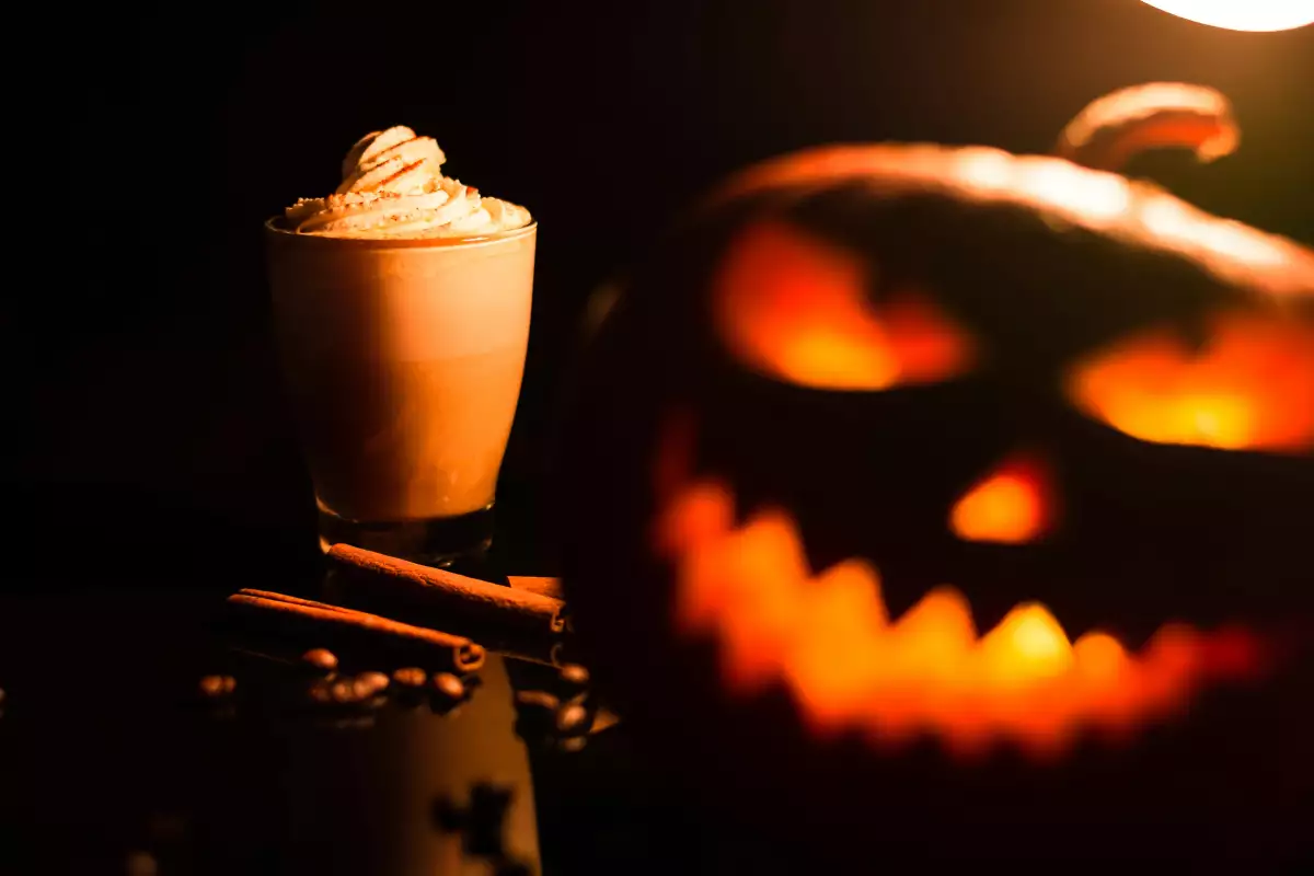 Foto de un vaso lleno de pumpkin spice latte y una calabaza de Halloween