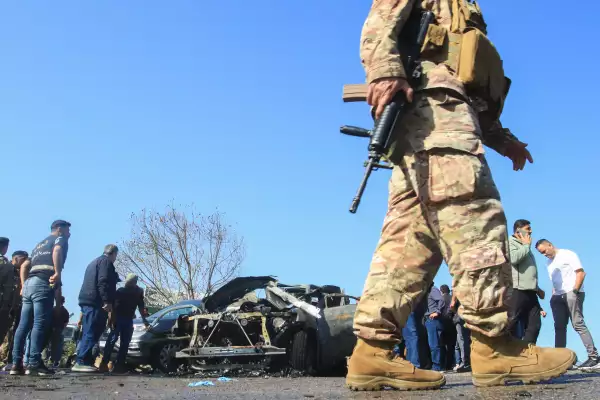 Varias personas inspeccionan un vehículo calcinado que, al parecer, fue alcanzado por un ataque israelí en Ghazieh, cerca de Sidón, el 18 de abril de 2025.