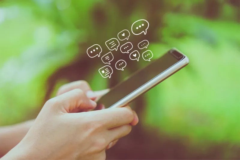 Women hand using smartphone typing, chatting conversation in chat box icons pop up. Social media maketing technology concept.Vintage soft color tone background.