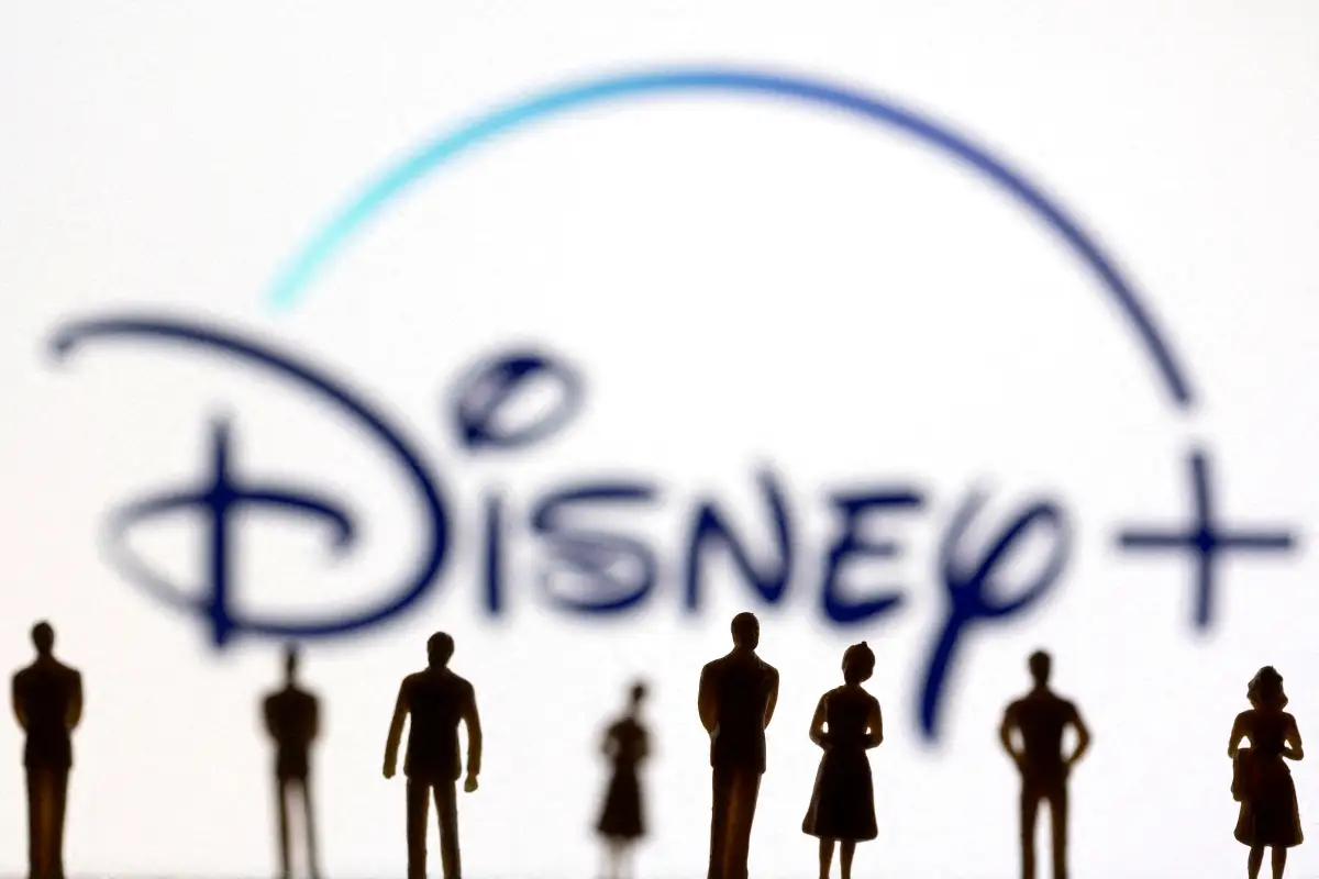 Las figuras de juguete de las personas se ven frente al logotipo de Disney + que se muestra, en esta ilustración tomada el 20 de enero de 2022.