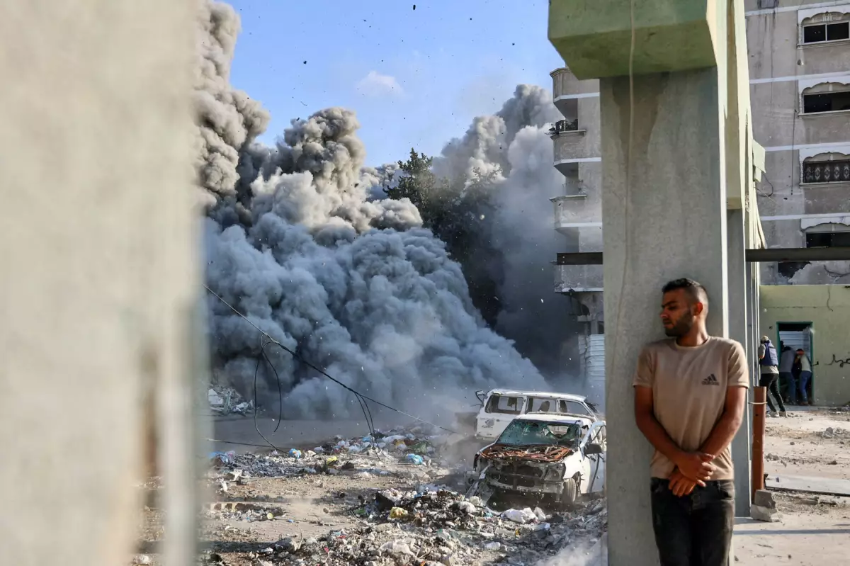 Un hombre se cubre detrás de una columna mientras una explosión propaga humo y polvo durante un ataque israelí que supuestamente tuvo como objetivo una escuela en el distrito de Zeitoun en las afueras de la ciudad de Gaza, el 1 de septiembre de 2024, en medio del conflicto en curso entre Israel y el grupo palestino Hamas.