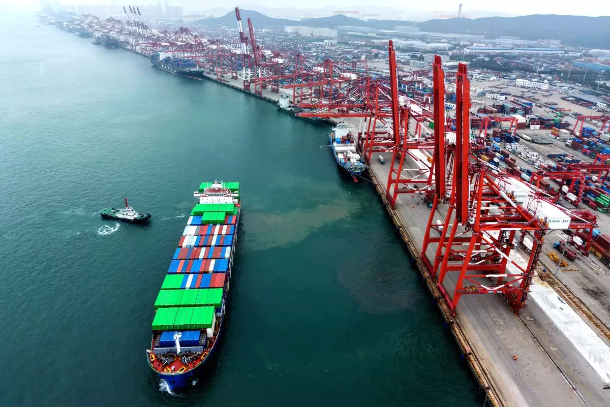 Un barco se mueve en posición en la terminal de contenedores del puerto en Qingdao, en la provincia oriental de Shandong de China, el 11 de octubre de 2025. China acusó a los Estados Unidos de "doble rasero" el 12 de octubre, después de que el presidente Donald Trump amenazara con un arancel adicional del 100 por ciento en la segunda economía más grande del mundo.