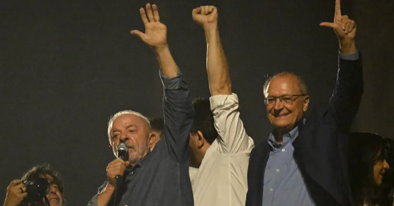 Lula da Silva levanta mano izquierda en la cual se observa la falta de su dedo meñique. Lo acompaña el vicepresidente.jpg