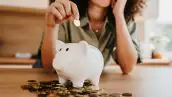 Worried young woman saving last coins in piggy bank