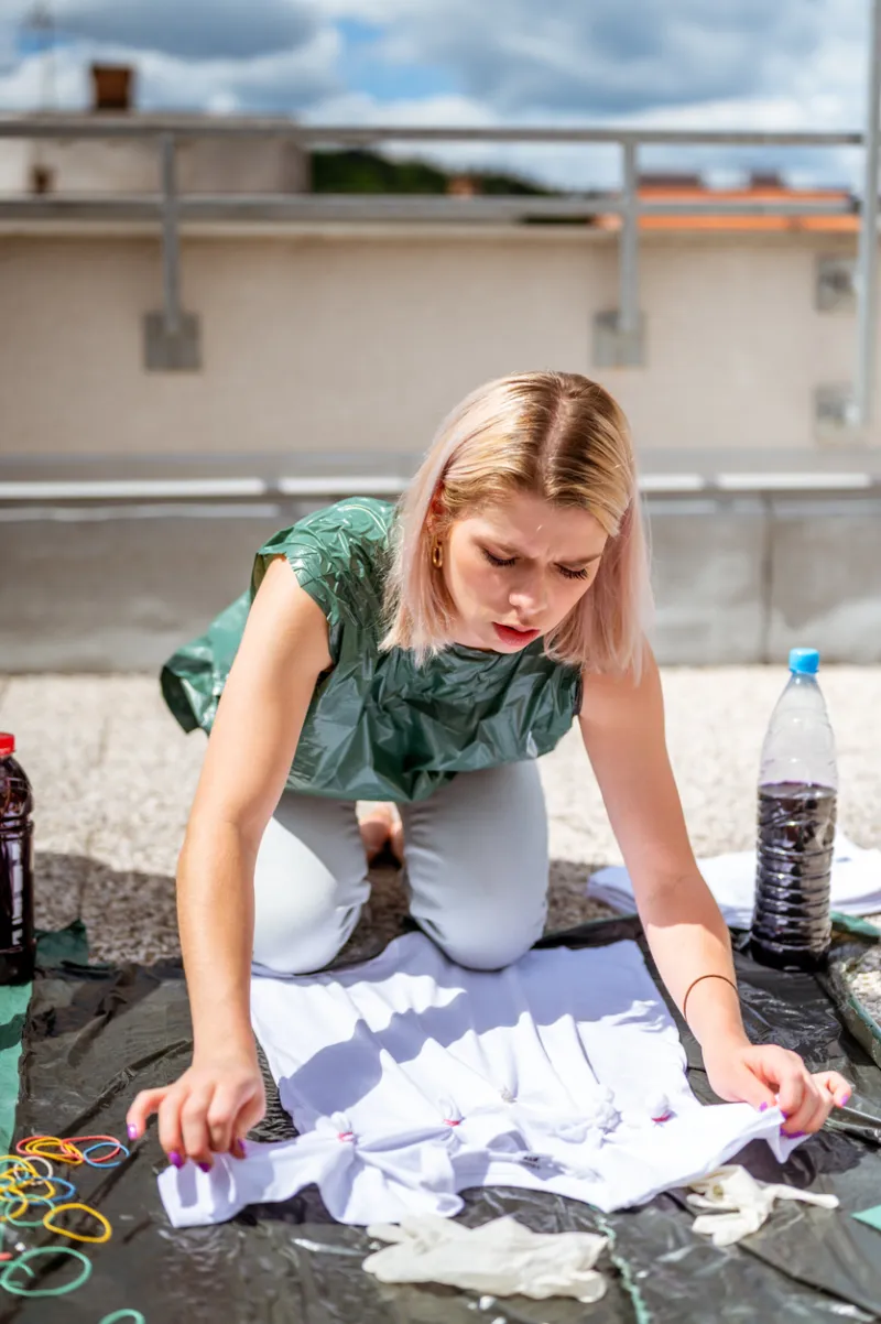 Young adult woman making tie dye clothes outdoors on the rooftop
