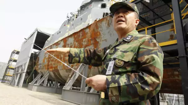 Un elemento surcoreano muestro los restos del buque hundido en marzo