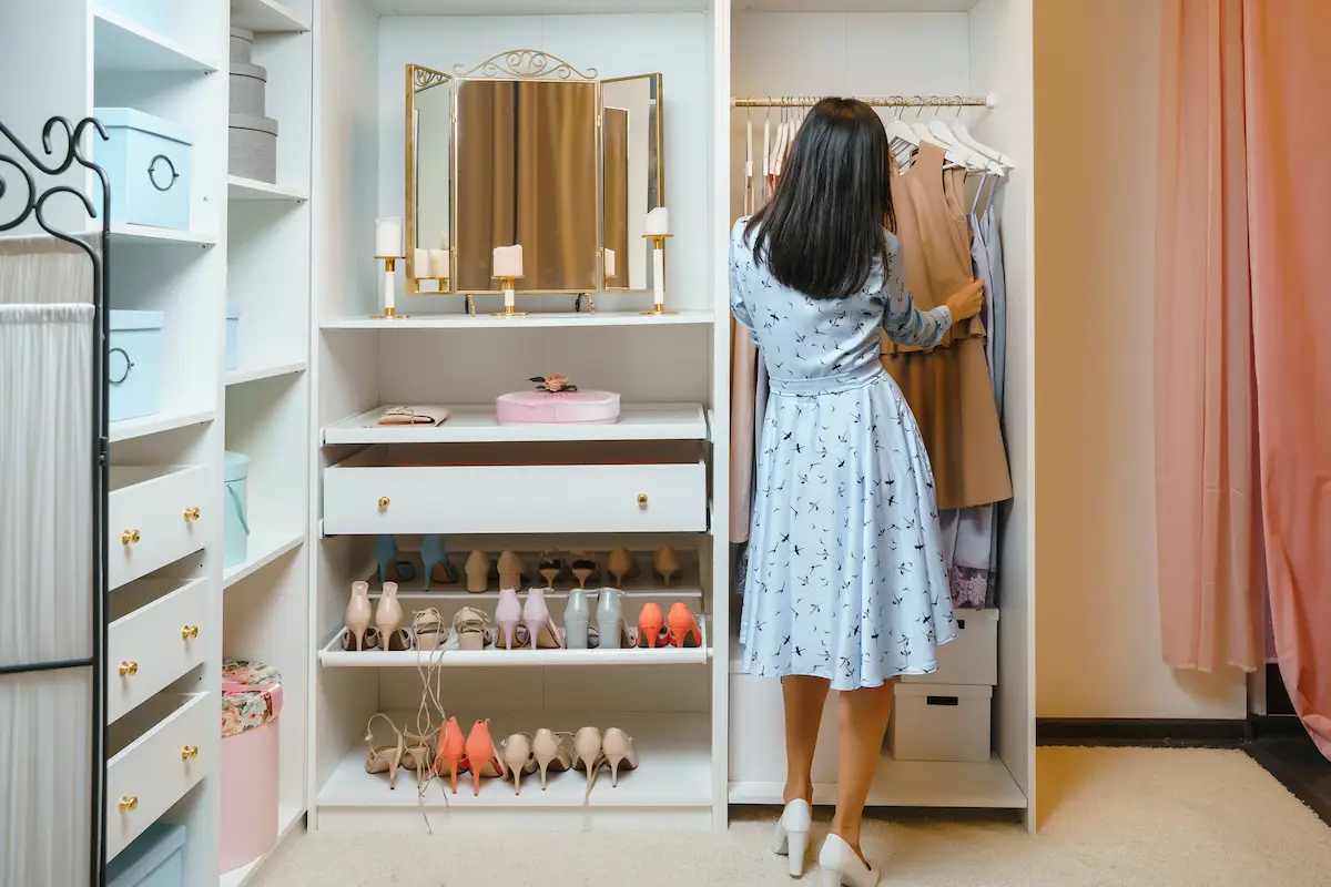 Attractive woman choosing a dress in a dressing room or store. View from the back. Fashion, style and space organization concept