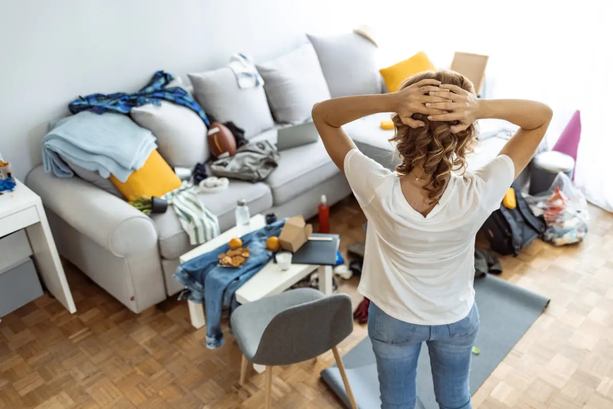 Mujer estresada en su habitación con todo tirado.