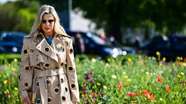 Máxima de holanda con un conjunto azul y una gabardina con múltiples agujeros. 