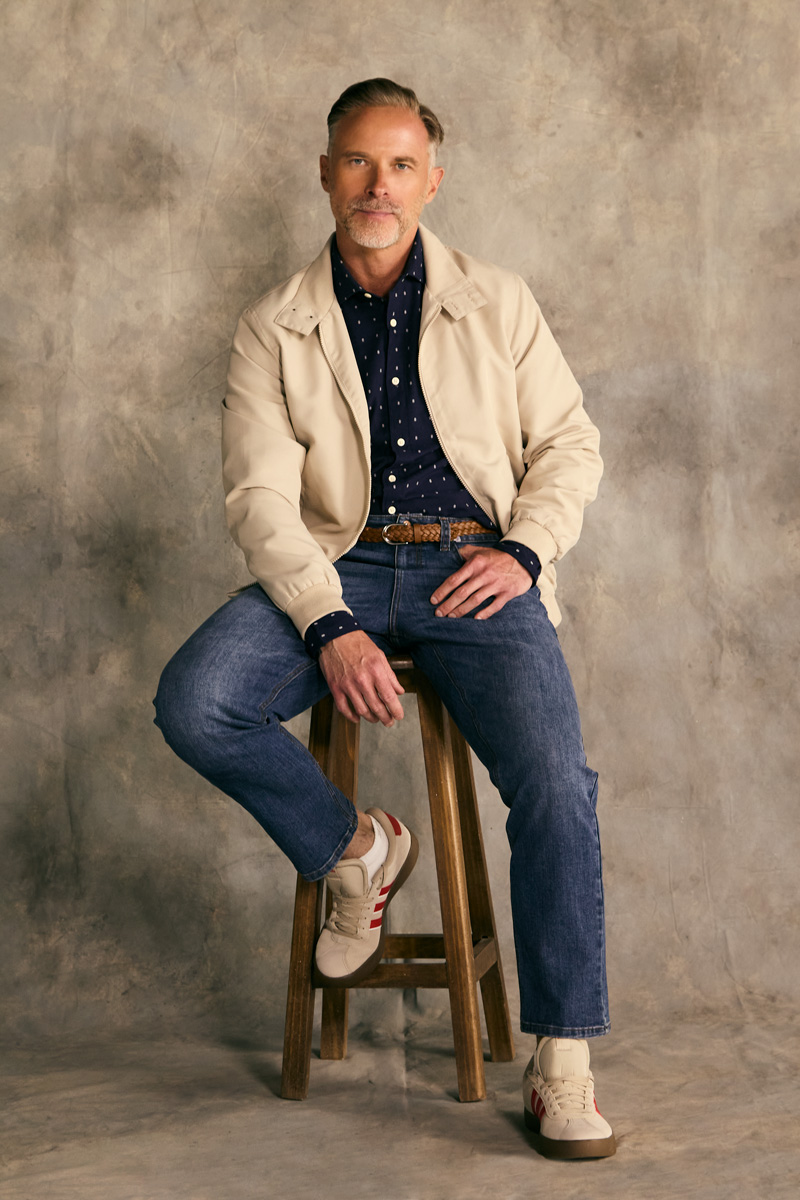 Papá todoterreno sentado en banco con jacket beige, camisa azul y jeans